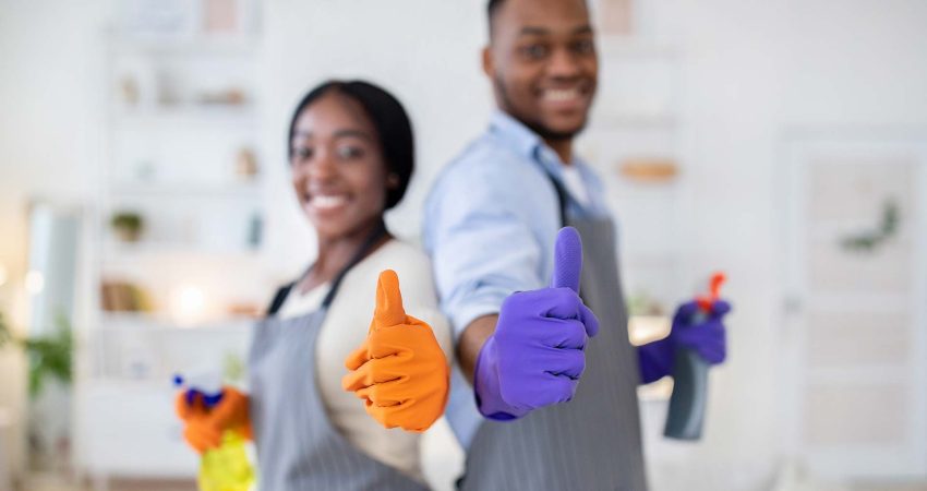 happy professional cleaners giving thumbs up to the camera